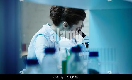 scientist looking in microscope near blurred colleague in laboratory,stock image Stock Photo