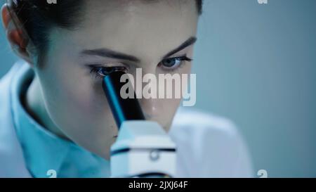 close up of female scientist looking through microscope in clinic,stock image Stock Photo