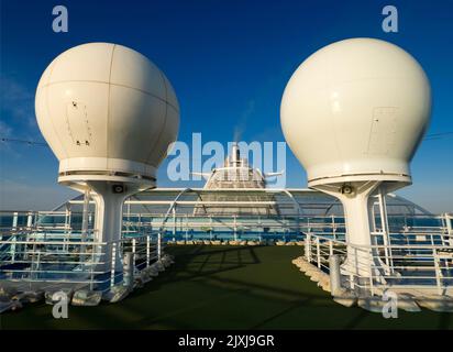 Think of the most surreal spot for a putting course. How about the top deck of a cruise liner? Well, this is the view from on, dominated by the ship's Stock Photo