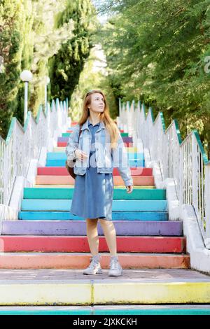 Woman on multi-colored steps. Concrete colored staircase. Blonde woman in jeans Stock Photo