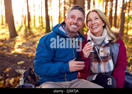 Mature Retired Couple Stop For Rest And Hot Drink On Walk Through Fall Or Winter Countryside Stock Photo