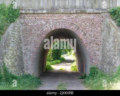 A medieval brick tunnel over a footpath under the bright sunlight Stock Photo