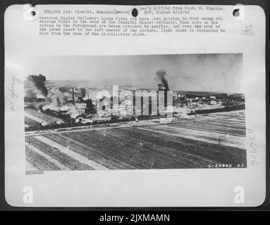 Creditul Minier Refinery-Large fires are here seen gaining headway among oil storage tanks in the rear of the Creditul Minier refinery. Tank cars on the siding in the foreground are being attacked by gunfire, and over the roof of the power plant to Stock Photo