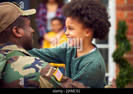 American Soldier In Uniform Returning Home To Family On Hugging Children Outside House Stock Photo