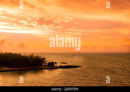 Bright orange tropical sunset over ocean and island Stock Photo