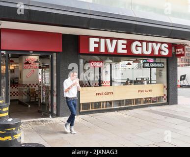 Man leaving Five Guys restaurant carrying a drink in Newcastle, England, UK Stock Photo