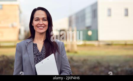 Portrait Of Female Team Leader Or Manager Standing Outside Offices Or Factory With Clipboard Stock Photo