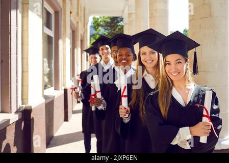 Portrait of happy female and male university graduates holding diplomas of higher education. Stock Photo