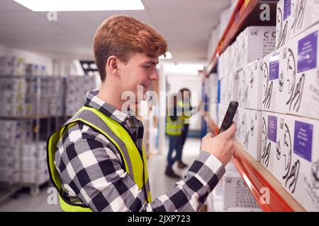 Male Worker Inside Busy Warehouse Scanning Box Barcode On Handheld Device Stock Photo