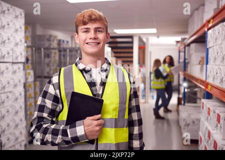 Portrait Of Male Worker Inside Busy Warehouse Checking Stock On Shelves Using Digital Tablet Stock Photo