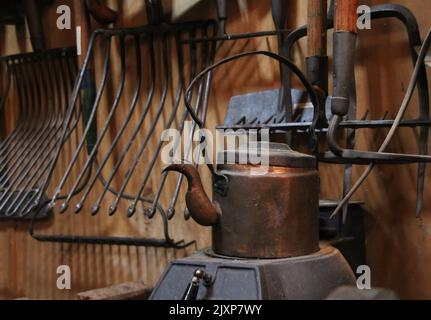 Antique workshop with old tools and tea pot on a gas coal stove Stock Photo