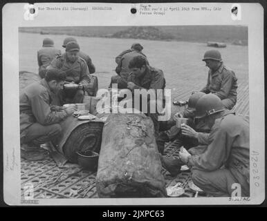Aviation Engineers Of The Ix Engineer Command, Building An Airstrip In Germany For 9Th Af Fighter Bombers, Have Their Noonday Chow In The Open. Food Is Served On The Line With Rolls Of Prefabricated Bituminous Surfacing (Pbs) As 'Tables.' Stock Photo