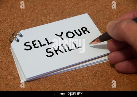 Hand writing sell your skill text on white notepad. Skill concept. Stock Photo