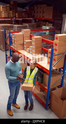 Male Team Leader With Digital Tablet In Warehouse Training Intern Standing By Shelves Stock Photo