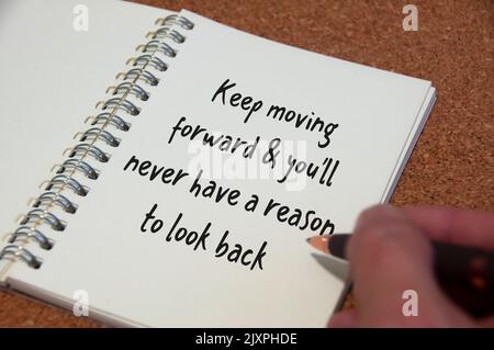 Keep moving forward and you will never have a reason to look back text written on white notebook. Inspirational concept. Stock Photo