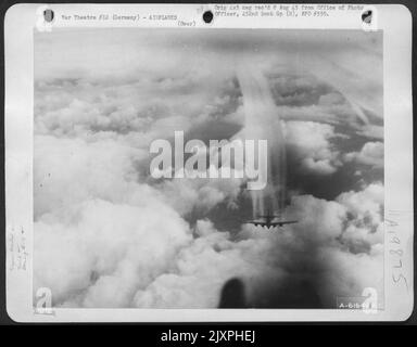 With Dense Cloud Formations Below It A Boeing B-17 Flying Fortress, Part Of A Formation Of The 452Nd Bomb Group Leaves Contrails Of Condensing Vapor To Mingle With The Clouds As The Formation Drones Toward Its Objective Of Frankfurt, Germany, 20 March 194 Stock Photo