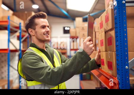 Male Worker Wearing Inside Warehouse Scanning Stock Barcode On Shelves Using Digital Tablet Stock Photo