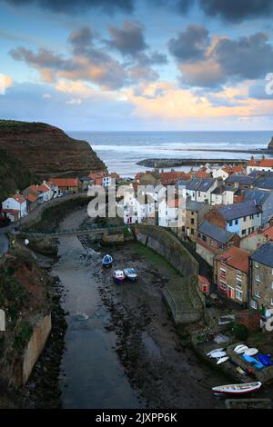 Clouds over the village of Staithes on the North Yorkshire Coast illuminated by the setting sun. Stock Photo