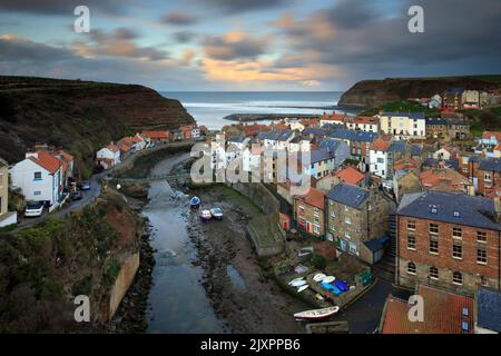 Clouds over the village of Staithes on the North Yorkshire Coast illuminated by the setting sun. Stock Photo