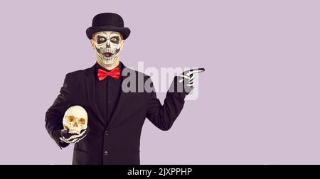 Man in Halloween costume with surprised and shocked expression is pointing at advertising space. Stock Photo