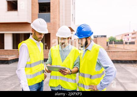 Group of professional engineer architects discussing plan at construction site Stock Photo