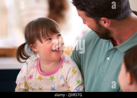 Father With Down Syndrome Daughter Sitting Around Table At Home Stock Photo