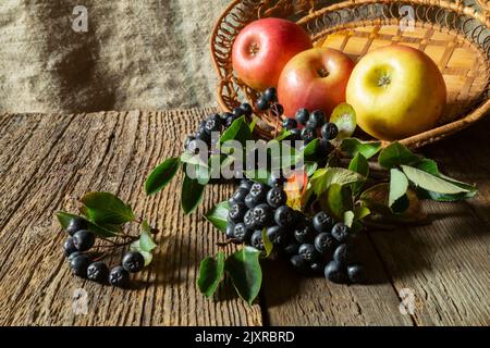 Still life of apples and mountain ash on an old board. Ripe fruit on the background of burlap Stock Photo
