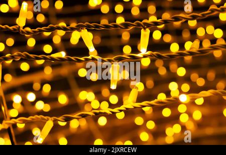 Defocused street light bulbs decor, string of golden lights on dark background Stock Photo