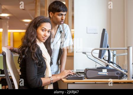 Teenage Students: Computer Studies. Classmates making use of their college library. From a series of high school education related images. Stock Photo