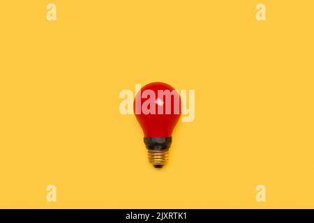 A red lightbulb on a yellow background with copy space Stock Photo
