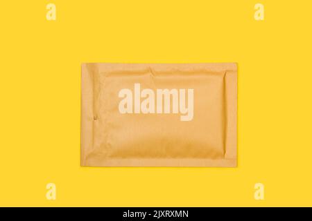 A brown padded envelope on a yellow background with copy space Stock Photo