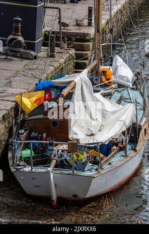 shabby old sailing yacht on the quay at wareham in dorset, old cruising yacht with deck covered in sails and useful items, vintage wooden yacht. Stock Photo