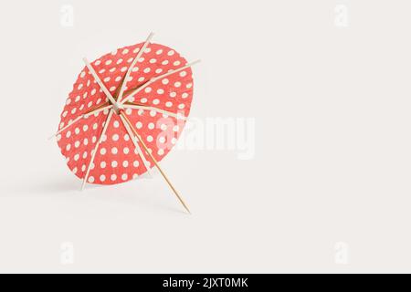 A red with white dots open cocktail umbrella on a white background Stock Photo