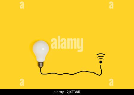Lightbulb connected with a black line cable shape to a wi-fi sign on a yellow background Stock Photo