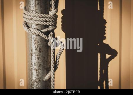 Coarse rope wrapped around wooden pole in vintage color.Blured background with a natural sunlight Stock Photo