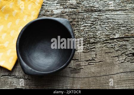 Black ceramic bowl on rustic wood background with decoration. Copy space. Stock Photo