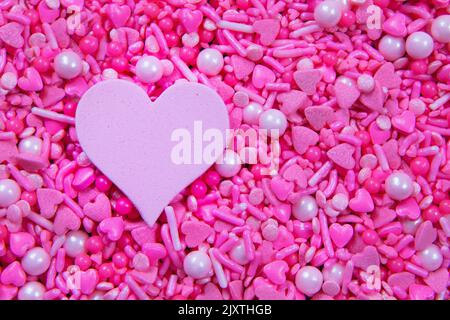 Full frame pink heart sprinkles and a pink heart shape, copy space Stock Photo