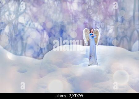 a guardian angel in a blue robe with a book in the snow on a background of multicolored brilliant lights. christmas decoration. postcard. Space for te Stock Photo