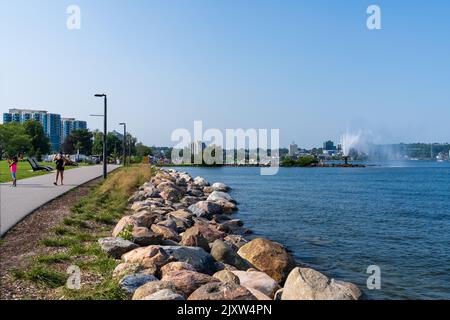 Barrie, Ontario, Canada - July 25 2021 : Walking Path on shore of Kempenfelt Bay, Lake Simcoe in summer time. Centennial Park Waterfront Fountain. Stock Photo