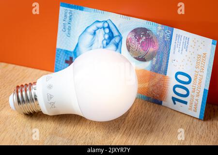 Swiss money 100 francs and a light bulb, concept of rising energy and electricity prices in Switzerland Stock Photo