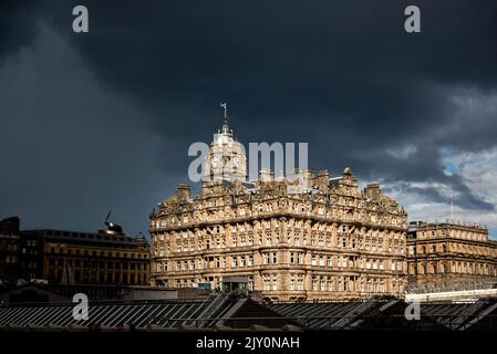Sunlight striking The Balmoral Hotel on Princes Street with rain clouds approaching. Edinburgh, Scotland, UK. Stock Photo