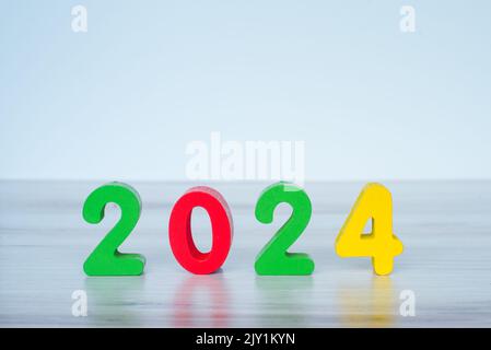 2024 standing colored block numbers on light wooden and white background Stock Photo