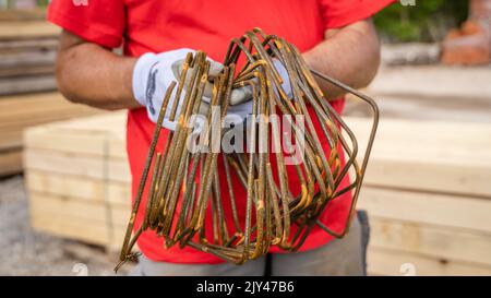 one man hold iron metal reinforcement armature at warehouse or construction site copy space close up on midsection and hands Stock Photo