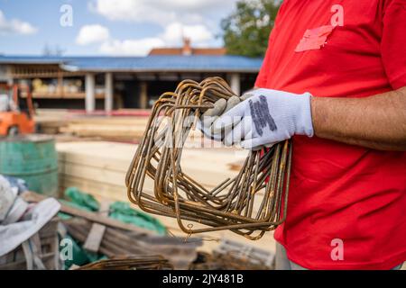 one man hold iron metal reinforcement armature at warehouse or construction site copy space midsection of unknown person Stock Photo