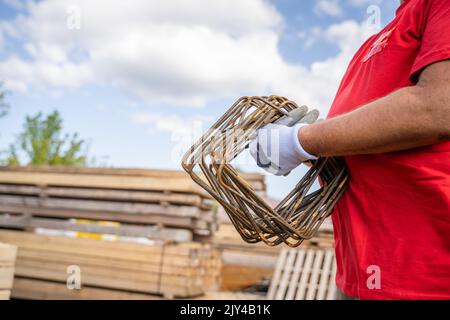 one man hold iron metal reinforcement armature at warehouse or construction site copy space midsection of unknown person Stock Photo