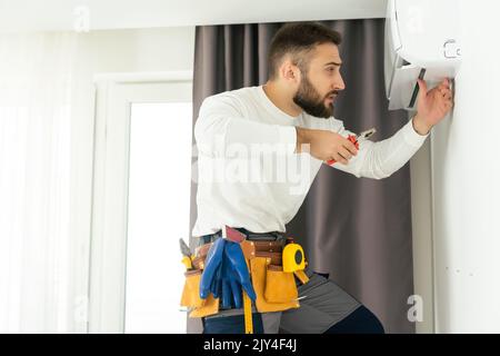 technician service checking and repairing air conditioner indoors. Stock Photo