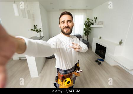 Smiling handsome young builder making selfie with mobile phone Stock Photo