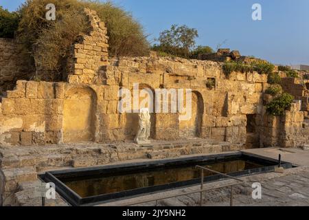 CAESAREA, Israel - August 2022, Roman emperor statue reflecting in a pool, Numerous tourists visit ruins fortress built by Herod the Great near Caesar Stock Photo