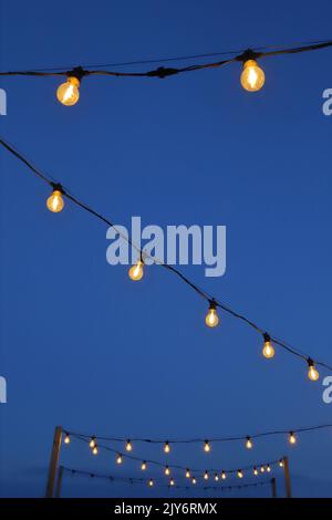 Outdoor string light bulbs against blue sky Stock Photo
