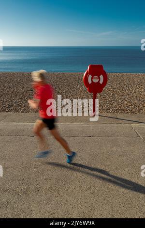 Blurred runner on a pebble beach of the Jurassic Coast in Lyme Regis, Dorset Stock Photo